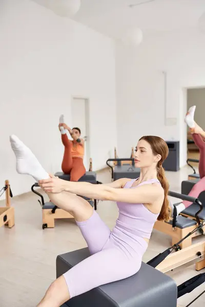 Um grupo de mulheres bonitas e esportivas em um ginásio que se envolve em uma lição de pilates, com foco na força e flexibilidade. — Fotografia de Stock