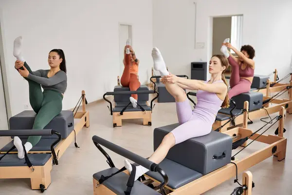 Athletic women gracefully exercising during a Pilates session in a gym. — Stock Photo