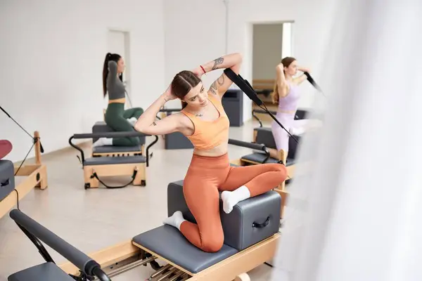 A diverse group of sporty women engage in a pilates class, focusing on flexibility and core strength. — Stock Photo