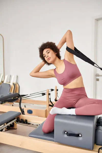Eine sportliche Frau in rosa Top und Leggings auf Pilates-Kurs. — Stockfoto