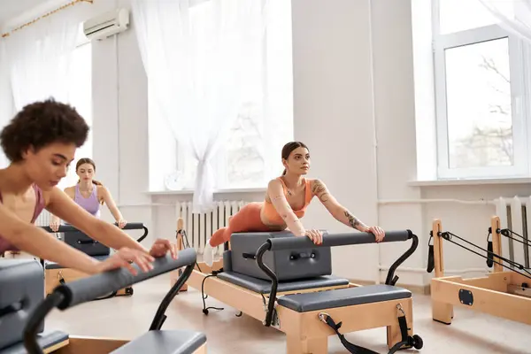 Apelando a las mujeres en ropa deportiva durante pilates en un gimnasio juntos. - foto de stock