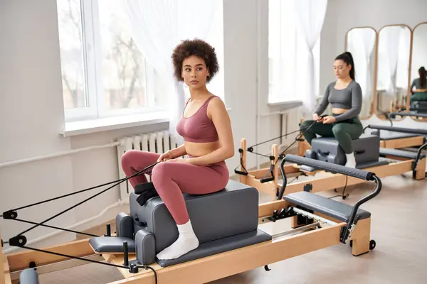 Attraktive Frauen in kuscheliger Kleidung üben gemeinsam Pilates im Fitnessstudio. — Stockfoto
