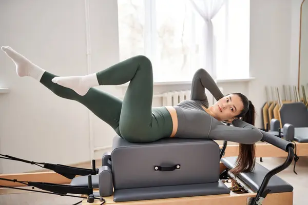 Mulher atraente no confortável sportswear praticando durante a aula de pilates. — Fotografia de Stock