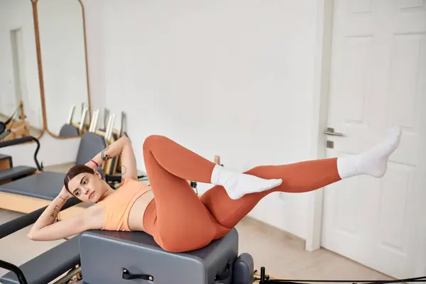 Mujer atractiva en ropa deportiva cómoda practicando durante la lección de pilates. - foto de stock
