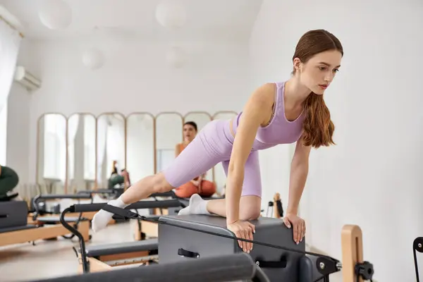 Alluring women in cozy attire practicing pilates in a gym together. — Stock Photo