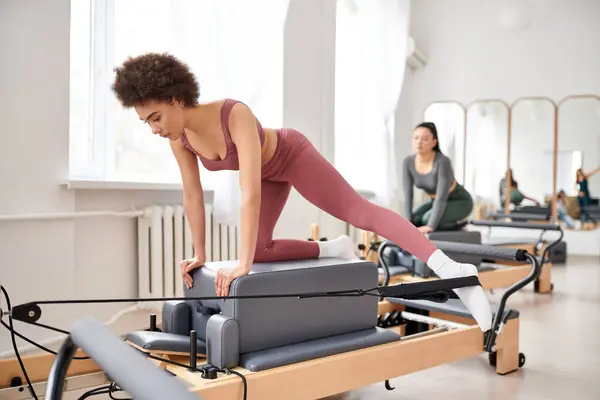 Fit women in cozy attire practicing pilates in a gym together. — Stock Photo