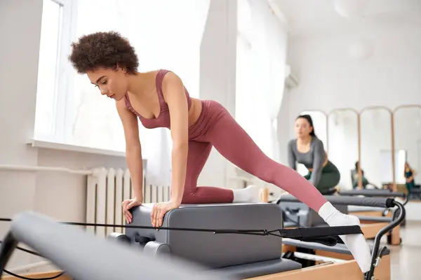 Young women in cozy attire practicing pilates in a gym together. — Stock Photo