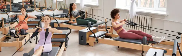 Sportliche Frauen führen anmutig Übungen während einer Pilates-Einheit in einem Fitnessstudio aus. — Stockfoto
