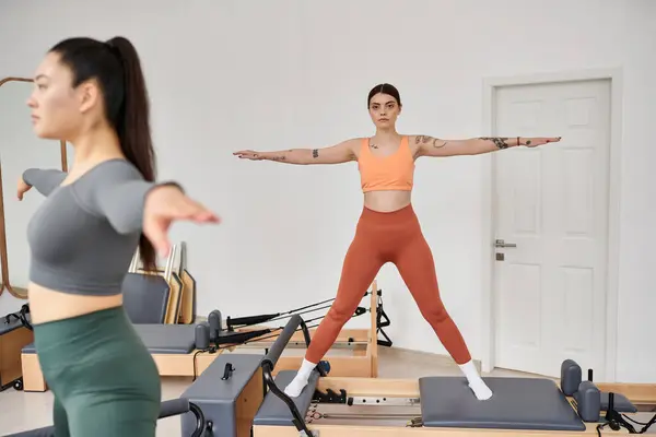 Jeunes femmes pratiquant gracieusement pilates dans une salle de gym ensemble. — Photo de stock