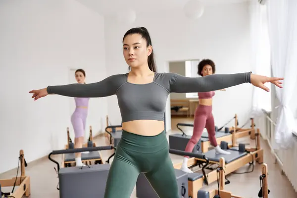 A vibrant group of sporty women engaged in a dynamic pilates session in a gym class. — Stock Photo
