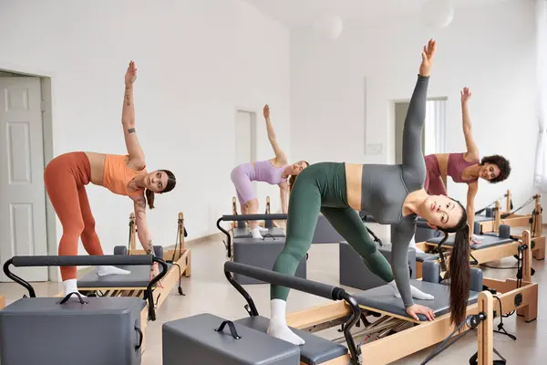 Eine dynamische Gruppe ziemlich sportlicher Frauen in einem Fitnessstudio, die verschiedene Pilates-Übungen praktizieren. — Stockfoto