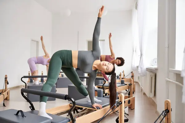 Gruppe hübscher, sportlicher Frauen in einem Fitnessstudio bei einer Pilates-Einheit, die sich auf Körperkraft und Beweglichkeit konzentriert. — Stockfoto