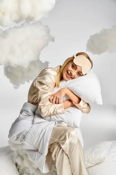 Una bella donna bionda in pigiama accogliente rilassarsi sopra un cuscino. — Foto stock