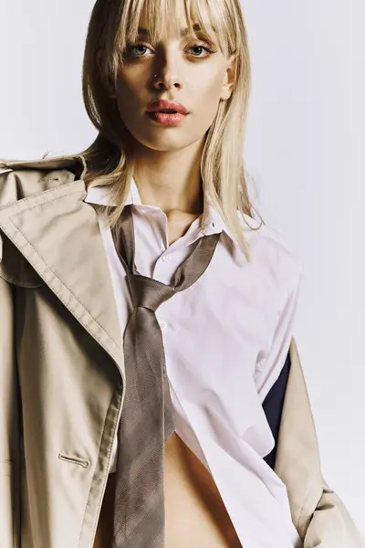 Attractive woman wearing tie and trench coat poses gracefully. — Stock Photo