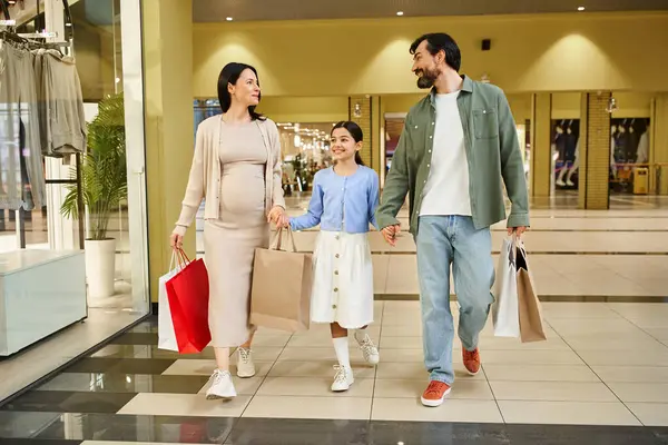 A cheerful family, laden with shopping bags, strolls through a bustling mall on a fun shopping weekend. — Stock Photo