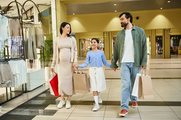 Щаслива сім'я насолоджується шопінгом у вихідні дні, прогулюючись по жвавому торговому центру з різними сумками. — стокове фото