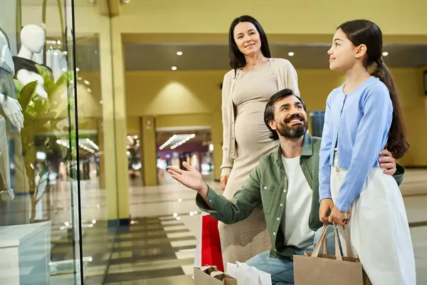 Una famiglia allegra cammina attraverso un centro commerciale con borse colorate. — Foto stock