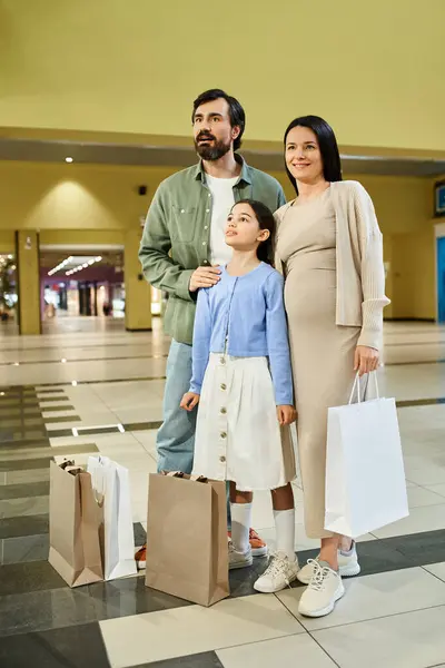 Una famiglia allegra con le borse della spesa si gode un weekend in un vivace centro commerciale, esplorando i negozi e facendo acquisti insieme.. — Foto stock