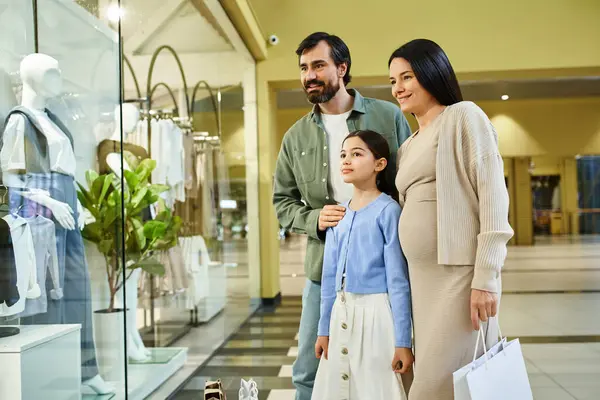 A joyful family browses through clothes in a bustling mall on a fun shopping outing. — Stock Photo