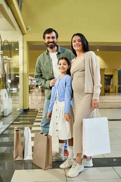 Una famiglia felice che trasporta le borse della spesa, passeggiando attraverso un centro commerciale affollato pieno di negozi e acquirenti. — Foto stock