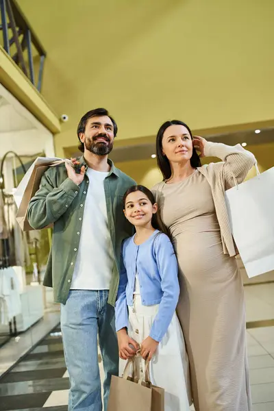 Una famiglia trasporta felicemente le borse della spesa mentre passeggia attraverso un vivace centro commerciale in una gita di fine settimana. — Foto stock