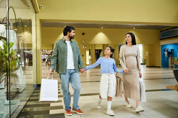 Une famille joyeuse se promène dans un centre commercial animé, portant des sacs colorés remplis de leurs trouvailles de week-end. — Photo de stock