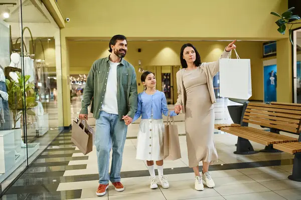 Una famiglia felice, ogni shopping bag in mano, cammina attraverso il vivace centro commerciale, godendo di un fine settimana di shopping insieme. — Foto stock