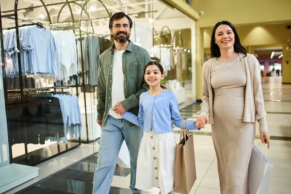 A happy family walks through a bustling shopping mall, joyfully holding shopping bags as they enjoy a weekend outing together. — Stock Photo
