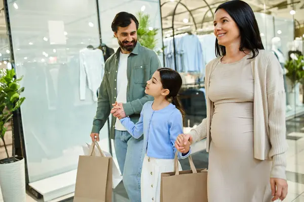A pregnant woman and her daughter stroll through a bustling shopping mall — Stock Photo