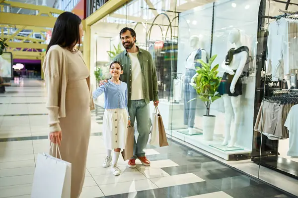 A man and woman shopping together with kid in a vibrant mall, browsing through stores and carrying shopping bags. — Stock Photo