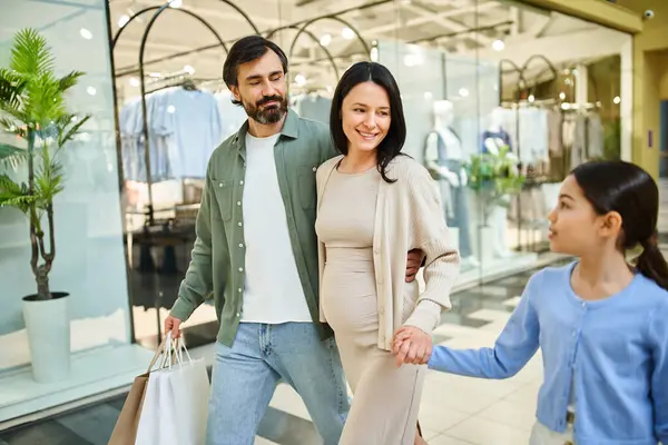 A pregnant woman and her daughter joyfully walk together in a bustling shopping mall on a fun family outing. — Stock Photo