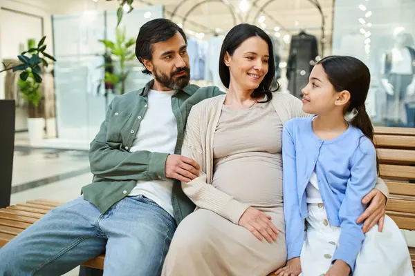 A pregnant woman and her daughter sit on a bench, enjoying a shopping weekend at the mall together. — Stock Photo