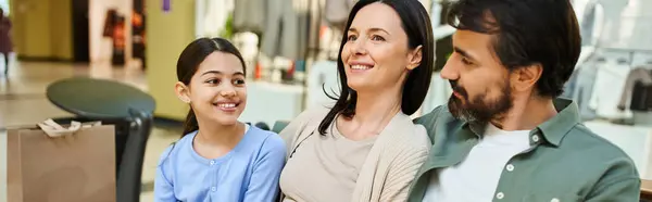 A happy family sits in the mall surrounded by shopping bags after a fun-filled day of shopping together. — Stock Photo