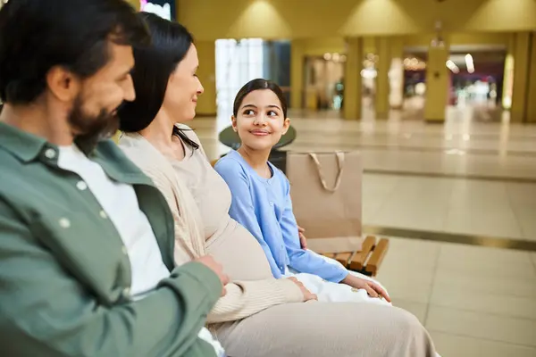 Une famille de contenu profite d'une pause sur un banc dans un centre commercial animé pendant un week-end amusant. — Photo de stock
