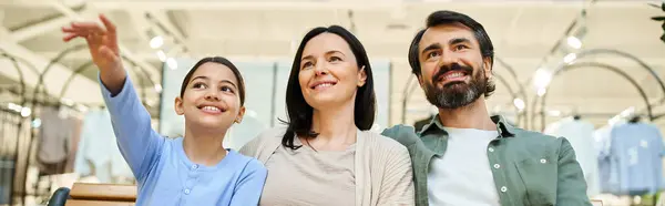 A cheerful family sits together on a mall bench, enjoying a shopping weekend outing. — Stock Photo
