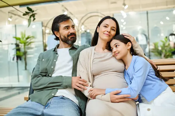 Une femme enceinte et sa fille s'assoient sur un banc, partageant un moment de calme dans un centre commercial animé. — Photo de stock