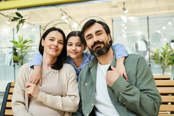 A cheerful family takes a break on a bench while enjoying a shopping outing together in a store. — Stock Photo