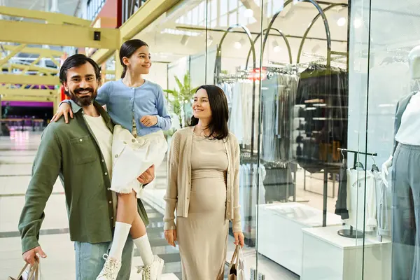 Щаслива сім'я, батьки та діти, неквапливо прогулюються через яскравий торговий центр, повний магазинів, людей та барвистих дисплеїв. — стокове фото