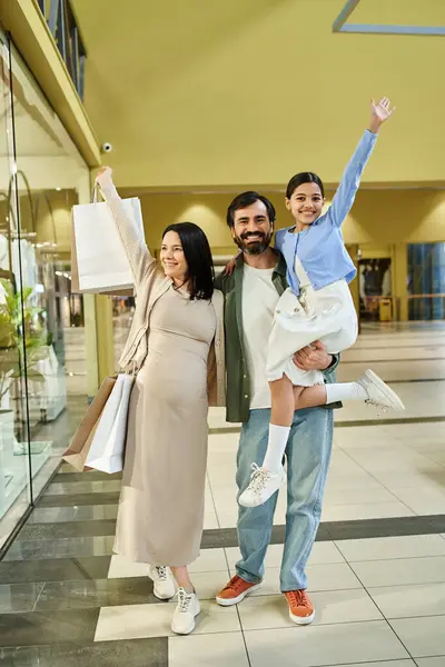 Una famiglia felice con un bambino porta le borse della spesa mentre passeggia attraverso un vivace centro commerciale in una gita di fine settimana. — Foto stock