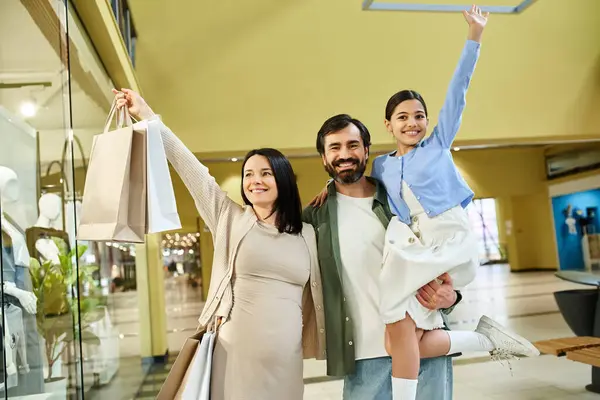 A happy family is seen holding shopping bags while exploring the mall together on a fun weekend outing. — Stock Photo