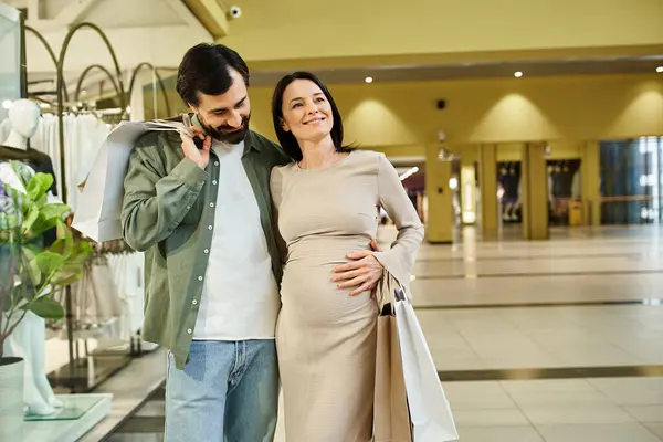Una donna incinta e un uomo godono di una piacevole passeggiata attraverso un vivace centro commerciale in una rilassante giornata di fine settimana. — Foto stock