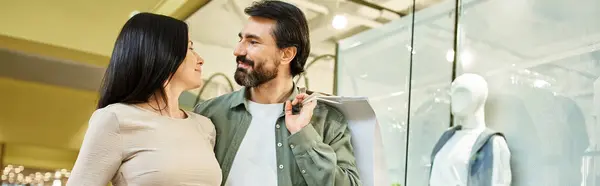 A man and woman share a tender moment as they lock eyes in a bustling shopping mall. — Stock Photo