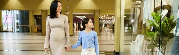 A woman and a child joyfully walking down a bustling mall, sharing a bonding moment amidst the shopping frenzy. — Stock Photo