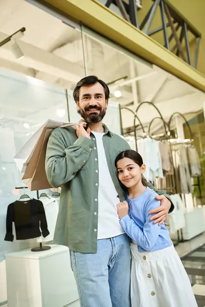 Un uomo gioioso e sua figlia stanno insieme di fronte a un vivace centro commerciale durante un divertente weekend in famiglia. — Foto stock