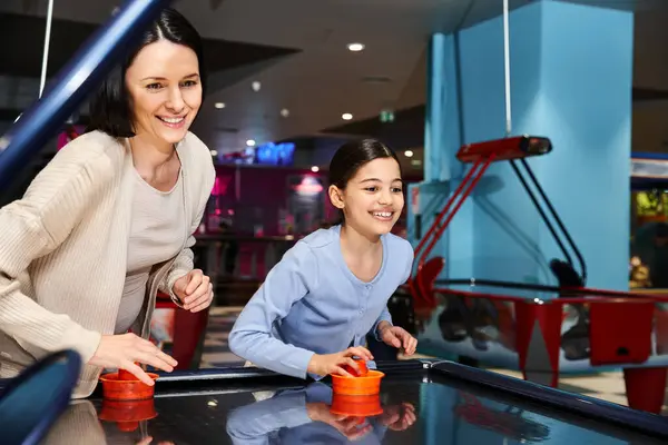 A happy mother and child play air hockey in a mall gaming zone during a weekend outing, enjoying quality time together. — Stock Photo