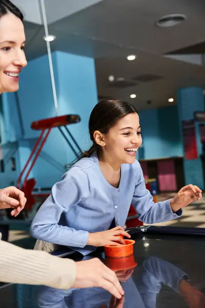 A woman and a girl share laughs and excitement as they face off in an intense game of air hockey at the malls gaming zone. — Stock Photo