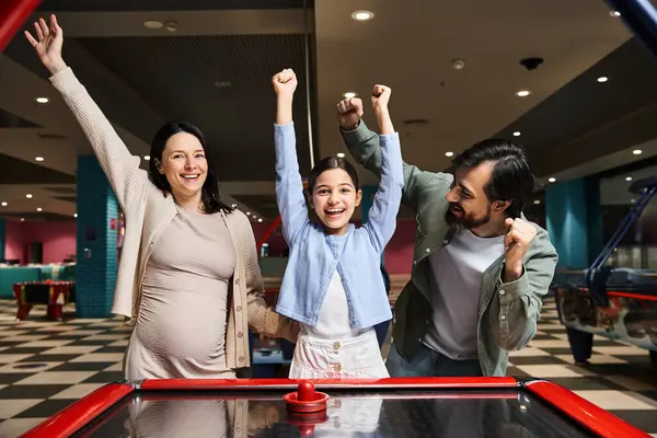 Uma família feliz desfrutar de um jogo animado de hóquei no ar na zona de jogos movimentada do shopping durante o fim de semana. — Fotografia de Stock