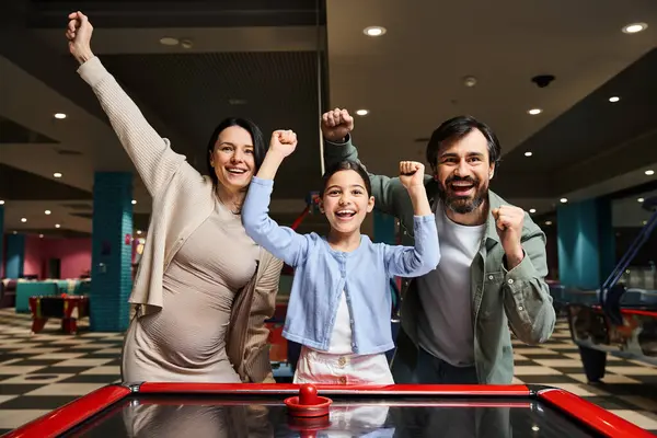 Uma família alegre compete em um animado jogo de hóquei aéreo em uma arcada, cercado por luzes piscando e o som do riso. — Fotografia de Stock