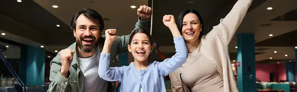 Une famille ravie lève les bras dans une zone de jeu de centres commerciaux, célébrant l'unité et le bonheur lors d'une sortie de week-end. — Photo de stock