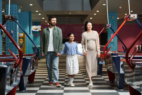 A happy family is joyfully walking through a air hockey in a mall during the weekend, enjoying a day of fun together. — Stock Photo